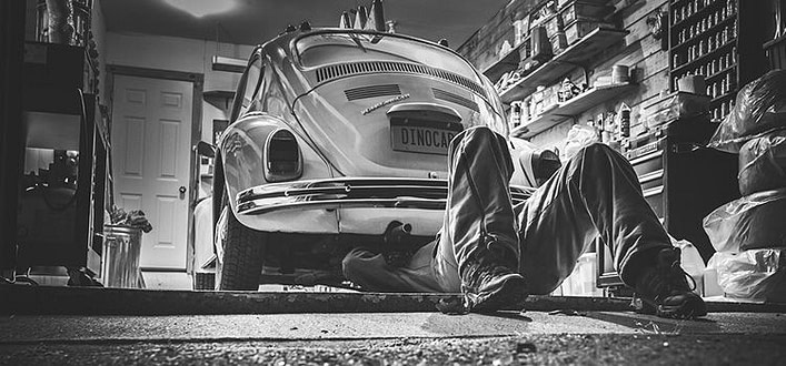 Amare incondizionatamente Amare incondizionatamente-foto in bianco e nero di auto d'epoca in officina con meccanico sdraiato sotto a ripararla