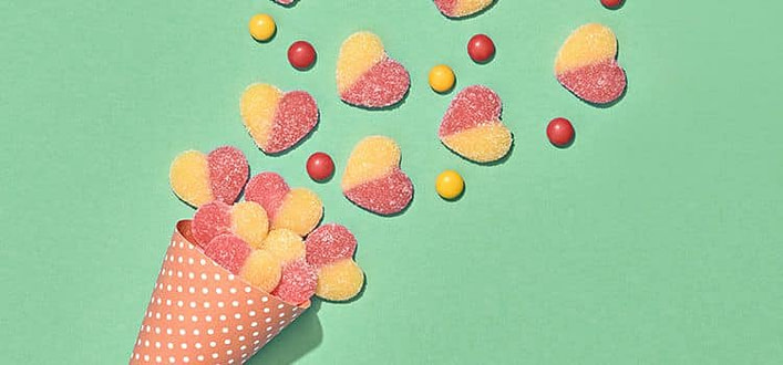 Amare incondizionatamente incondizionatamente-cono di cartone con esplosione di caramelle a cuore gialle e rosa su sfondo verde