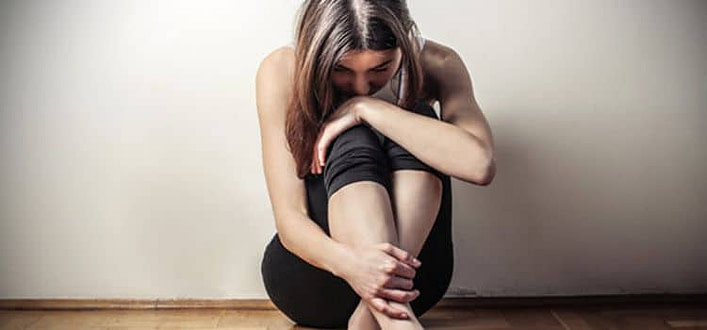 Come dimenticare un amore Come dimenticare un amore-ragazza rannicchiata a terra con la testa bassa un braccio sulle ginocchia e una mano tiene una caviglia