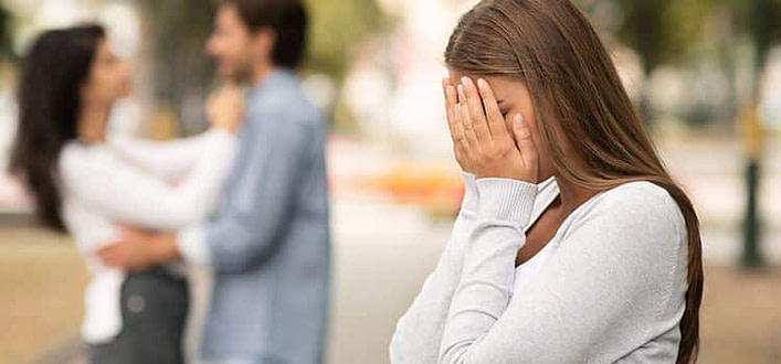 Non riesco a dimenticarlo Non riesco a dimenticarlo-ragazza di profilo affranta con volto tra le mani sullo sfondo altre persone sfuocate