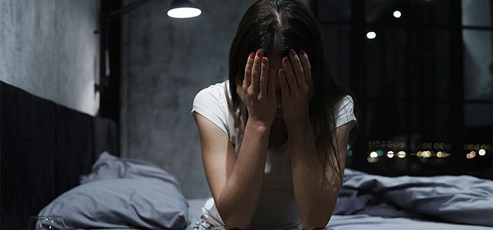 Differenza tra rimorso e rimpianto Differenza tra rimorso e rimpianto-ragazza in stanza buia con volto reclinato in avanti e coperto dalle mani