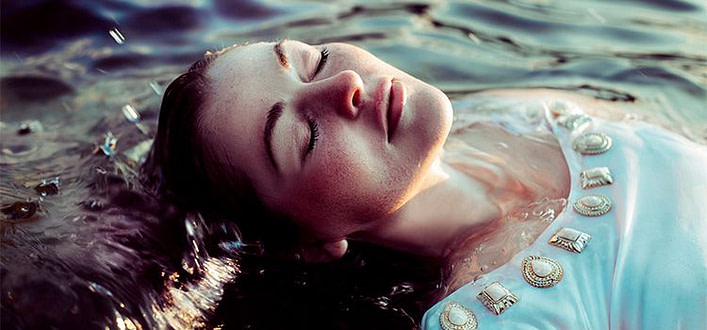 Lasciarsi andare Lasciarsi andare-ragazza fa il morto a galla sull'acqua lasciandosi andare con occhi chiusi e volto disteso