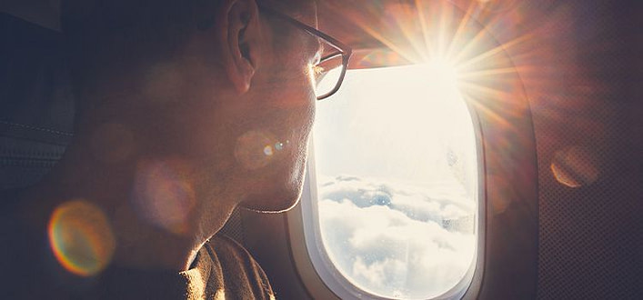 ritrovare se stesso Ritrovare se stesso-volto di ragazzo affacciato al finestrino dell’aereo con panorama di nuvole e raggi del sole che filtrano