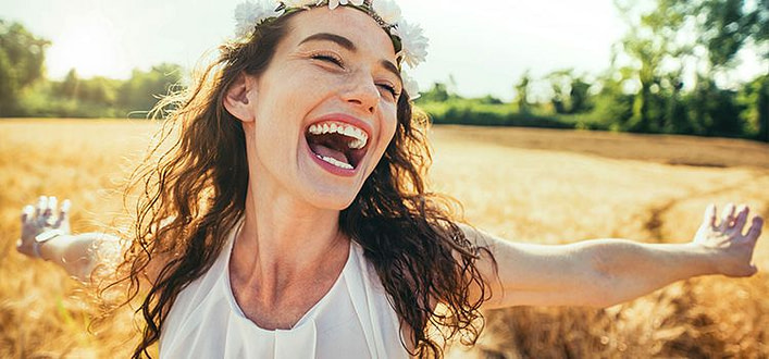 aforismi sulla felicità aforismi sulla felicità - Ragazza sorridente e felice con un campo di grano alle spalle