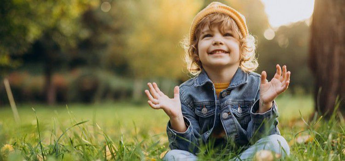 frasi di felicità-bambino con sorriso e sguardo felice seduto nell'erba frasi di felicità-bambino con sorriso e sguardo felice seduto nell'erba