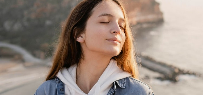 sentire la mancanza-ragazza serena con la testa inclinata sul lato e con il mare e una scogliera alle spalle sentire la mancanza-ragazza serena con la testa inclinata sul lato e con il mare e una scogliera alle spalle