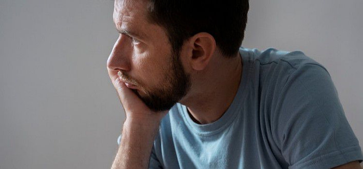 delusione-ragazzo di profilo seduto sul letto con sguardo crucciato e mano che sorregge il volto delusione-ragazzo di profilo seduto sul letto con sguardo crucciato e mano che sorregge il volto