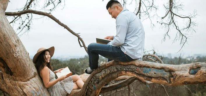 libri assolutamente da leggere-uomo e donna orientali seduti su un ramo mentre lui legge un libro libri assolutamente da leggere-uomo e donna orientali seduti su un ramo mentre lui legge un libro