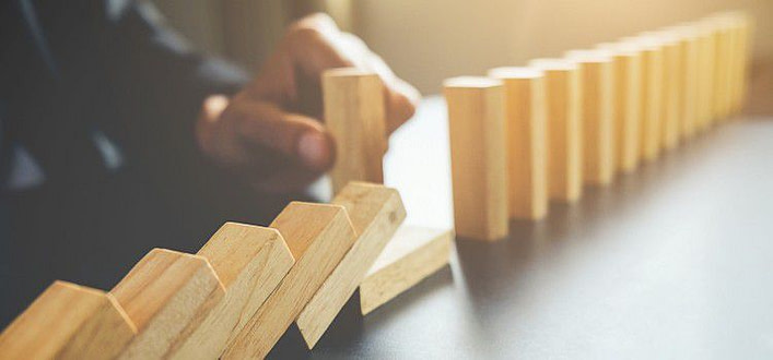 Ansia sul lavoro-mano che inserisce un pezzo di domino tra quelli in piedi e quelli caduti Ansia sul lavoro-mano che inserisce un pezzo di domino tra quelli in piedi e quelli caduti
