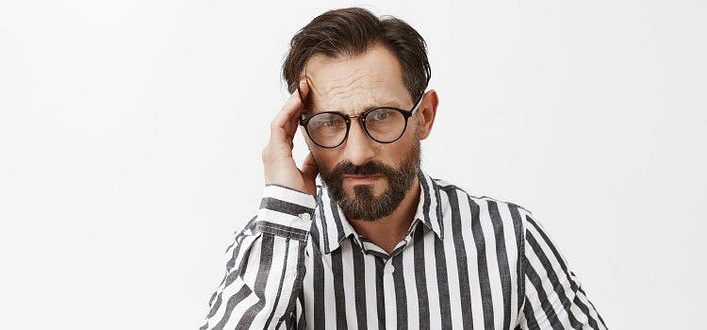 Tremore interno ansia-uomo con occhiali e barba preoccupato con mano appoggiata sulla tempia Tremore interno ansia-uomo con occhiali e barba preoccupato con mano appoggiata sulla tempia
