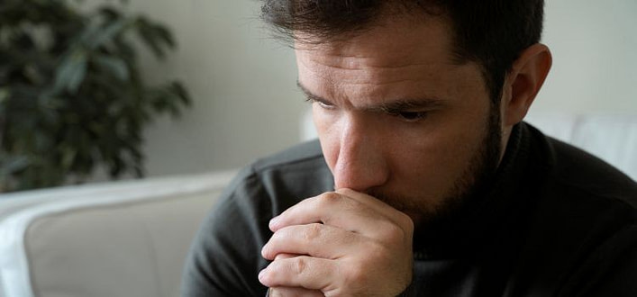 rimpianti e rimorsi-uomo pensieroso con mento appoggiato alle mani chiuse e sguardo abbassato rimpianti e rimorsi-uomo pensieroso con mento appoggiato alle mani chiuse e sguardo abbassato