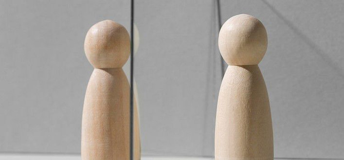 Come vincere l'egocentrismo-omini di legno di fronte uno all'altro e separati da un vetro Come vincere l'egocentrismo-omini di legno di fronte uno all'altro e separati da un vetro
