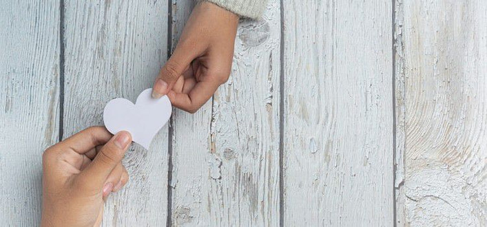 Amare incondizionatamente significato-mani uomo e donna che tendono un cuore bianco da due lati opposti Amare incondizionatamente significato-mani uomo e donna che tendono un cuore bianco da due lati opposti