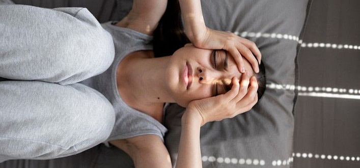 Disturbo d'ansia generalizzato sintomi-donna sul letto con mani alle tempie e ginocchia rannicchiate al petto Disturbo d'ansia generalizzato sintomi-donna sul letto con mani alle tempie e ginocchia rannicchiate al petto