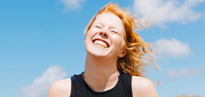 ragazza fulva sorride con occhi strizzati e volto girato verso l'alto cielo azzurro sullo sfondo ragazza fulva sorride con occhi strizzati e volto girato verso l'alto cielo azzurro sullo sfondo