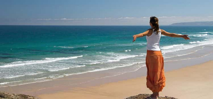 Come cambiare carattere Come cambiare carattere-ragazza di spalle in riva al mare guarda verso il cielo con braccia aperte