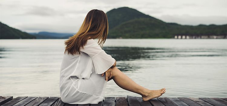 vivere in solitudine-ragazza rannicchiata a guardare il lago