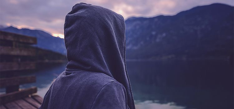 vivere la solitudine-ragazzo incappucciato che guarda un lago