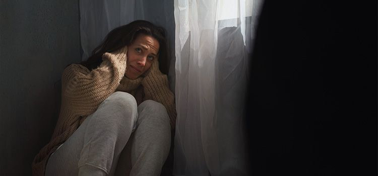 Aiuto ho paura - donna spevntata seduta sul pavimento con le mani alle tempie