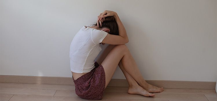 Come superare gli attacchi di panico da soli - Ragazza in panico per terra vicino a un muro