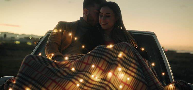 innamoramento significato - Coppia sotto una coperta sul cofano dell'auto