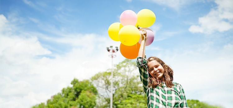 giornata della felicità - Una ragazza sorridente con dei palloncini in mano