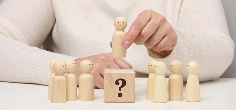 scelte difficili - un pupazztto di legno sopra un blocco di legno con raffigurato un punto interrogativo