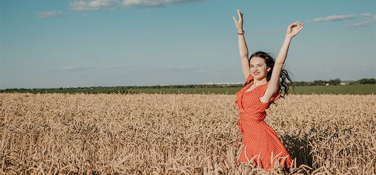 Come trovare la felicità - ragazza felice che cammina in un campo di grano