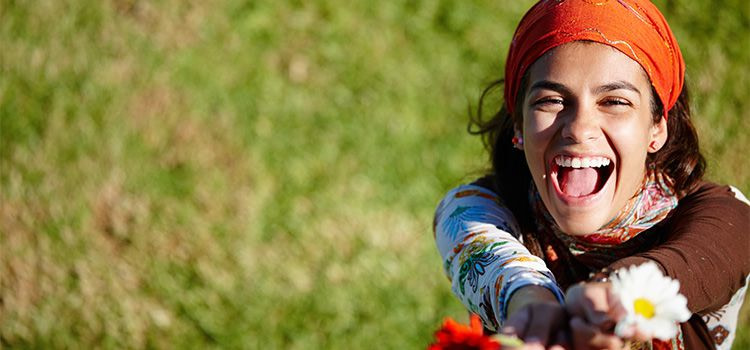 felicità significato - Ragazza sorridente con dei fiori di campo in mano