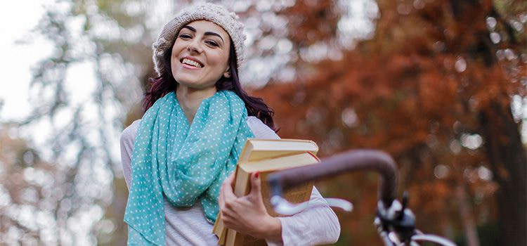 libri sulla felicità - ragazza sorridente che tiene in mano alcuni libri