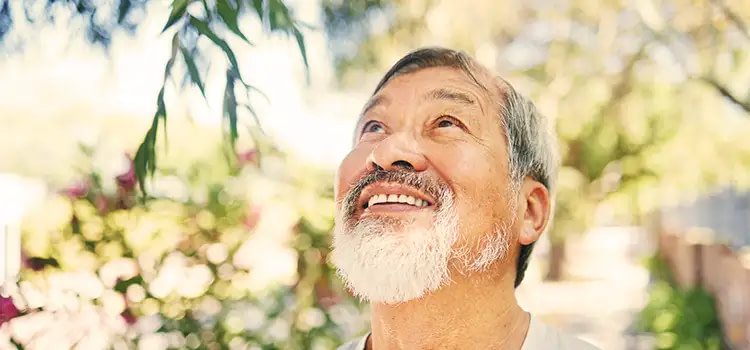 Come vivere bene - Un uomo adulto guarda sorridente verso il cielo