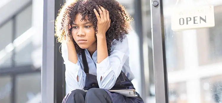 ansia lieve - Ragazza seduta su dei gradini con le mani sui lati della testa