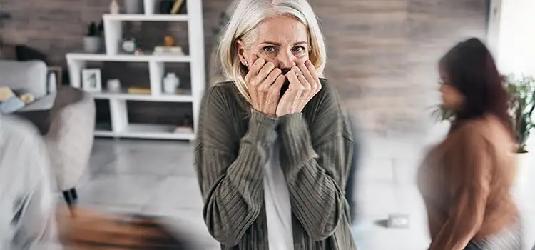 attacchi d'ansia cosa fare - Donna che si copre con la mani chiuse la bocca e guarda preoccupata in camera